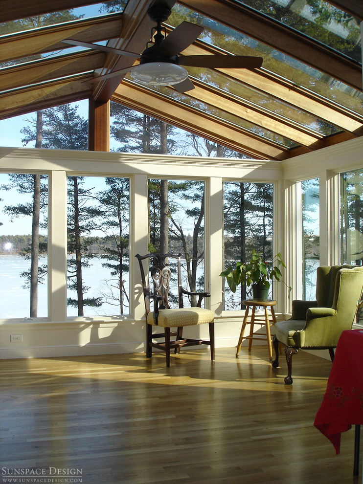 Photo of a mid-sized traditional sunroom in Boston with medium hardwood floors, a standard fireplace and a glass ceiling.