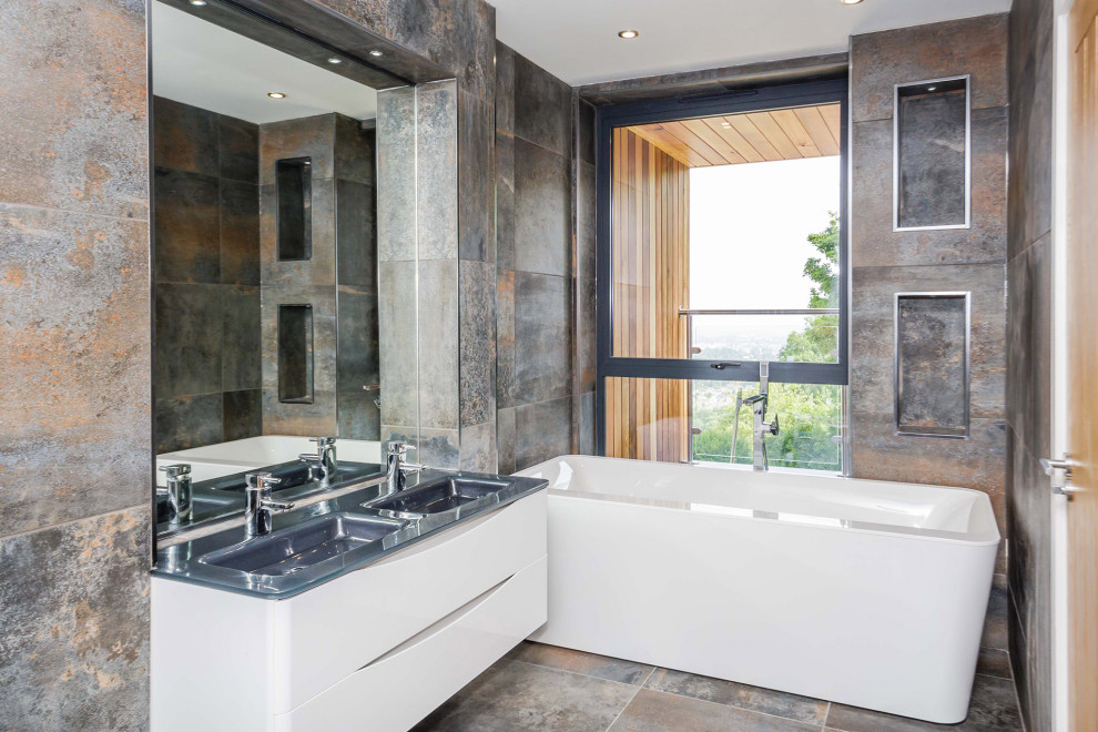 Inspiration for a mid-sized contemporary kids bathroom in Gloucestershire with white cabinets, a double shower, a one-piece toilet, stone tile, white walls, concrete floors, a drop-in sink, a sliding shower screen, a double vanity, a built-in vanity and a freestanding tub.