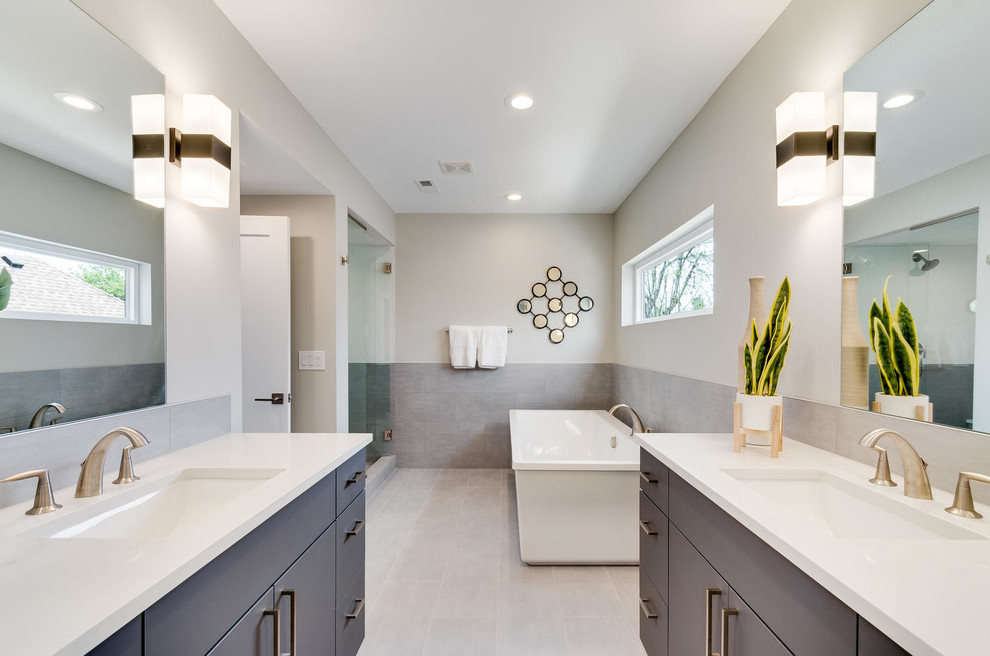 This is an example of a large transitional master bathroom in Denver with flat-panel cabinets, grey cabinets, a freestanding tub, a corner shower, an urinal, gray tile, porcelain tile, grey walls, porcelain floors, an undermount sink, engineered quartz benchtops, grey floor, a hinged shower door and white benchtops.