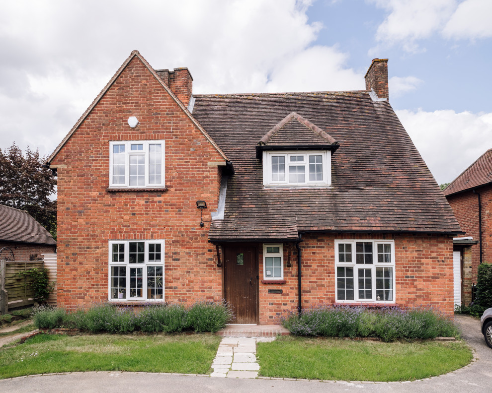 This is an example of a mid-sized traditional two-storey brick orange house exterior in Buckinghamshire with a gable roof and a tile roof.
