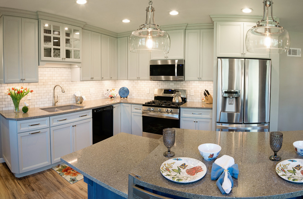 Example of a mid-sized transitional l-shaped vinyl floor eat-in kitchen design with an undermount sink, recessed-panel cabinets, gray cabinets, quartz countertops, white backsplash, marble backsplash, stainless steel appliances and an island
