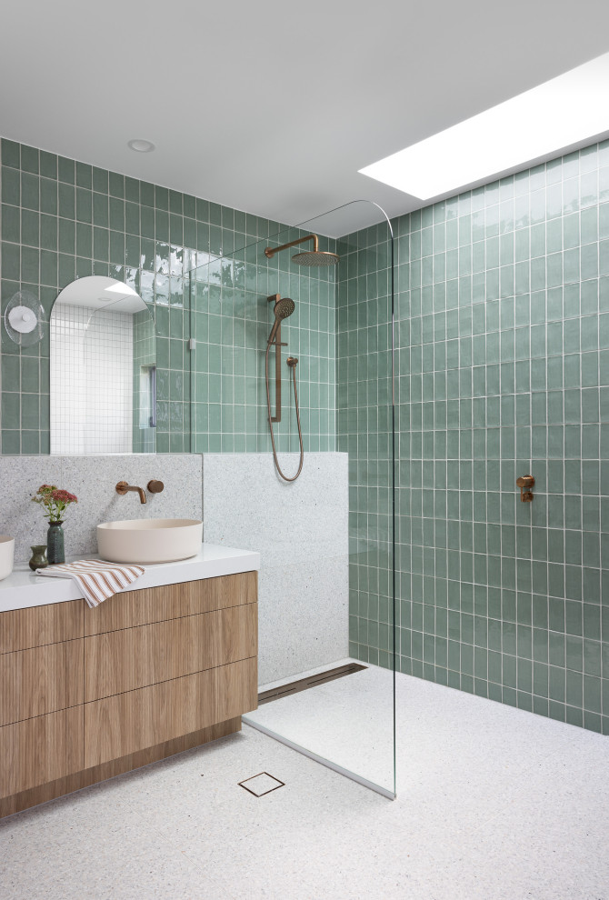 Modern inredning av ett vit vitt badrum, med släta luckor, skåp i mellenmörkt trä, en kantlös dusch, grön kakel, ett fristående handfat, vitt golv och med dusch som är öppen