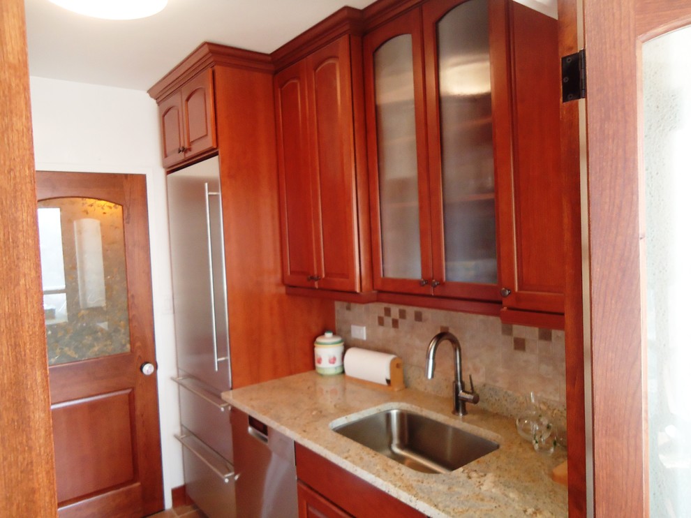 Traditional galley eat-in kitchen in New York with an undermount sink, raised-panel cabinets, brown cabinets, granite benchtops, beige splashback, ceramic splashback and stainless steel appliances.