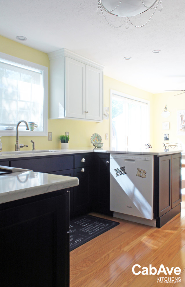 This is an example of a small transitional u-shaped eat-in kitchen in Other with an undermount sink, recessed-panel cabinets, black cabinets, quartz benchtops, yellow splashback, stainless steel appliances, medium hardwood floors, a peninsula and brown floor.