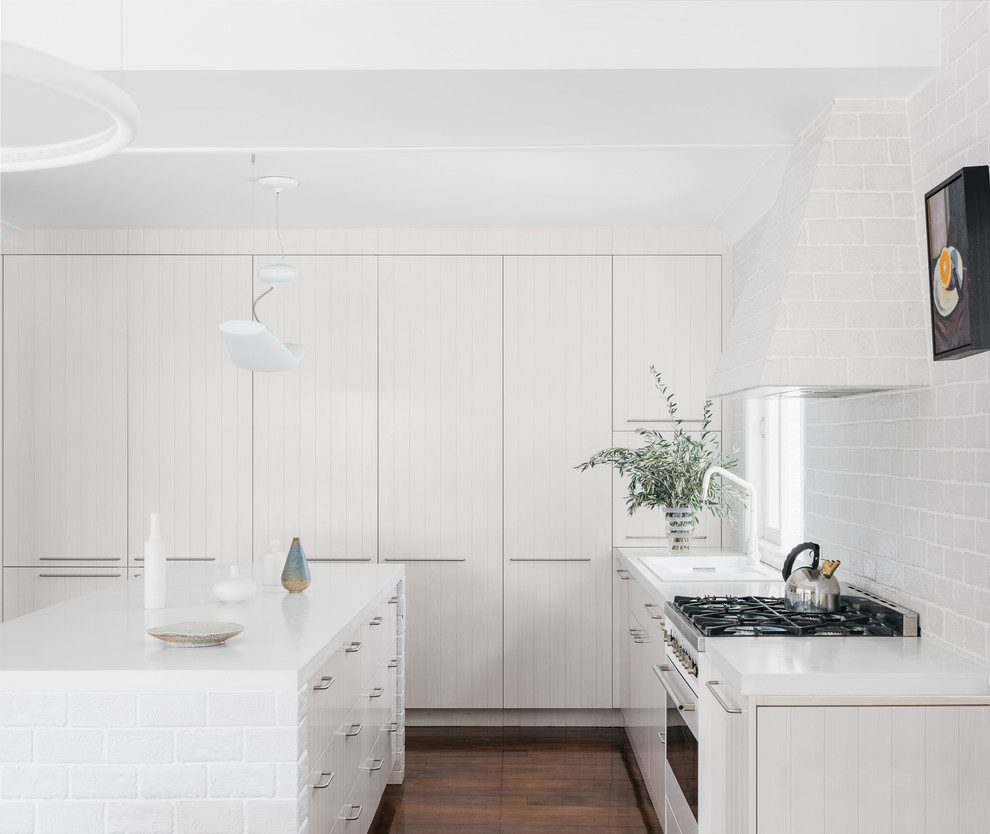 Inspiration for a large contemporary galley eat-in kitchen in Brisbane with a double-bowl sink, raised-panel cabinets, light wood cabinets, concrete benchtops, grey splashback, porcelain splashback, white appliances, dark hardwood floors, with island, brown floor and white benchtop.