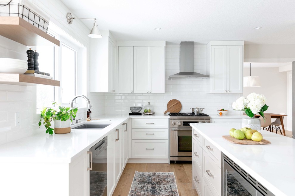 Eat-in kitchen - large transitional u-shaped medium tone wood floor and brown floor eat-in kitchen idea in Calgary with an undermount sink, shaker cabinets, white cabinets, quartzite countertops, white backsplash, subway tile backsplash, stainless steel appliances, an island and white countertops