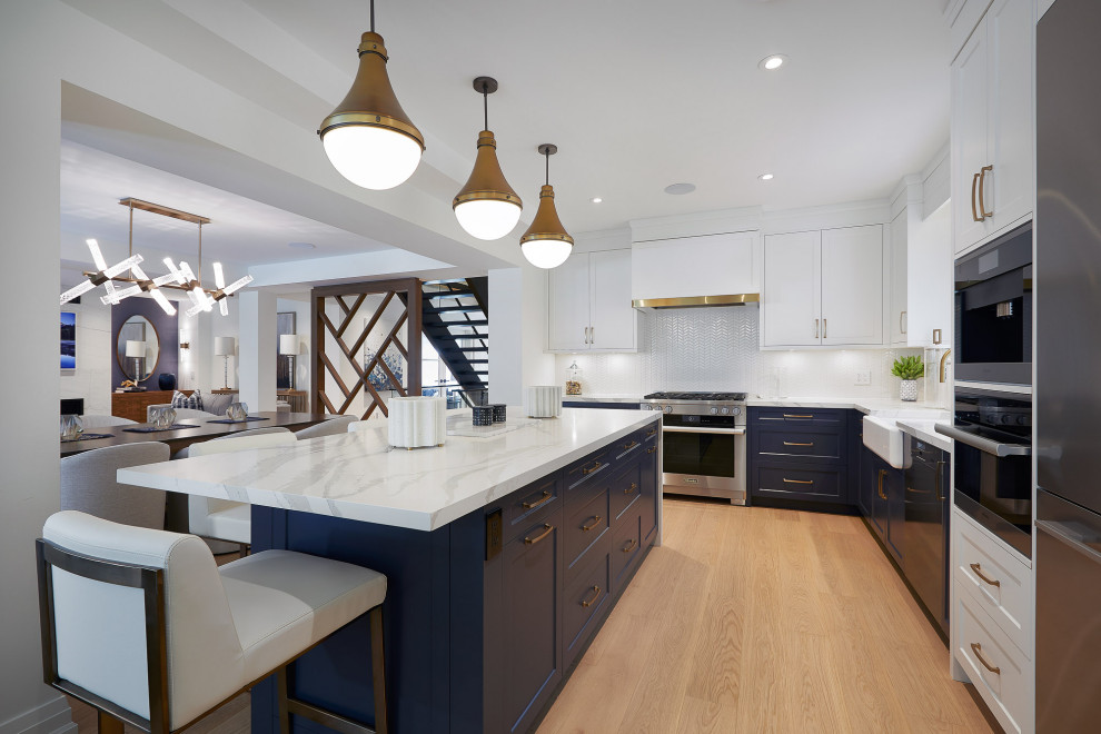Example of a large transitional l-shaped light wood floor eat-in kitchen design in Toronto with a farmhouse sink, recessed-panel cabinets, blue cabinets, white backsplash, stainless steel appliances, an island and white countertops