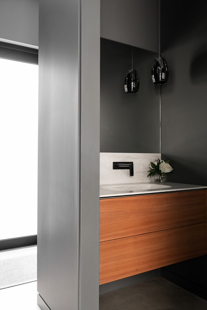 Industrial bathroom in Perth with medium wood cabinets, gray tile, ceramic tile, grey walls, concrete floors, an integrated sink, solid surface benchtops, grey floor and white benchtops.