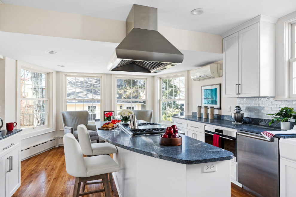 Inspiration for an u-shaped separate kitchen in Minneapolis with a farmhouse sink, shaker cabinets, white cabinets, granite benchtops, grey splashback, porcelain splashback, stainless steel appliances, dark hardwood floors, with island, brown floor and blue benchtop.