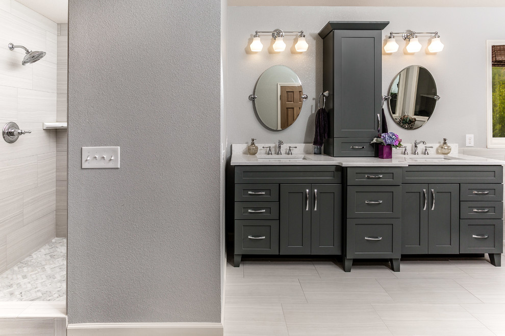 Example of a mid-sized transitional master white tile and porcelain tile porcelain tile freestanding bathtub design with an undermount sink, shaker cabinets, gray cabinets, quartz countertops, a one-piece toilet and gray walls