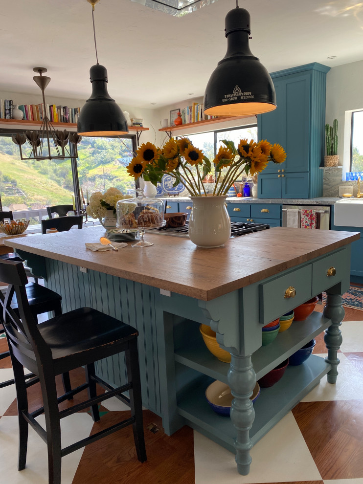 На фото: кухня среднего размера в стиле фьюжн с обеденным столом, фасадами в стиле шейкер, синими фасадами, деревянной столешницей и островом