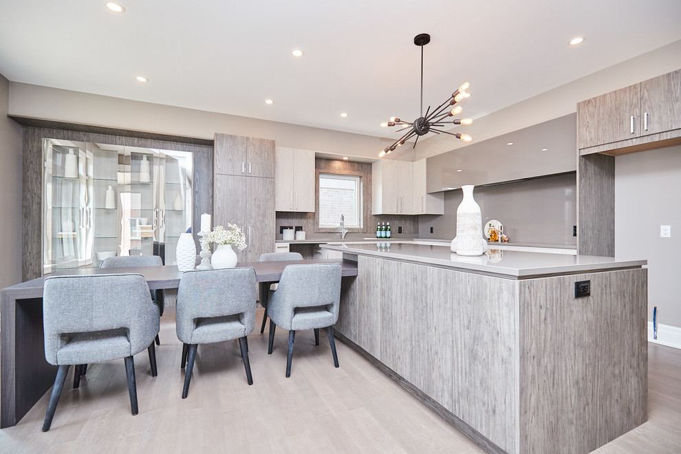 Eat-in kitchen - large transitional l-shaped medium tone wood floor and gray floor eat-in kitchen idea with an undermount sink, flat-panel cabinets, gray cabinets, quartzite countertops, gray backsplash, stainless steel appliances, an island and gray countertops