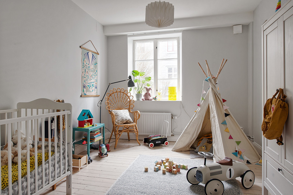 This is an example of a mid-sized scandinavian gender-neutral nursery in Gothenburg with grey walls, light hardwood floors and beige floor.