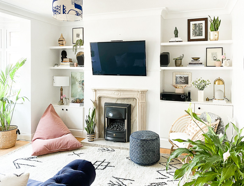 Inspiration for a medium sized eclectic enclosed living room in London with white walls, medium hardwood flooring, a standard fireplace, a stone fireplace surround, a wall mounted tv, brown floors and a chimney breast.