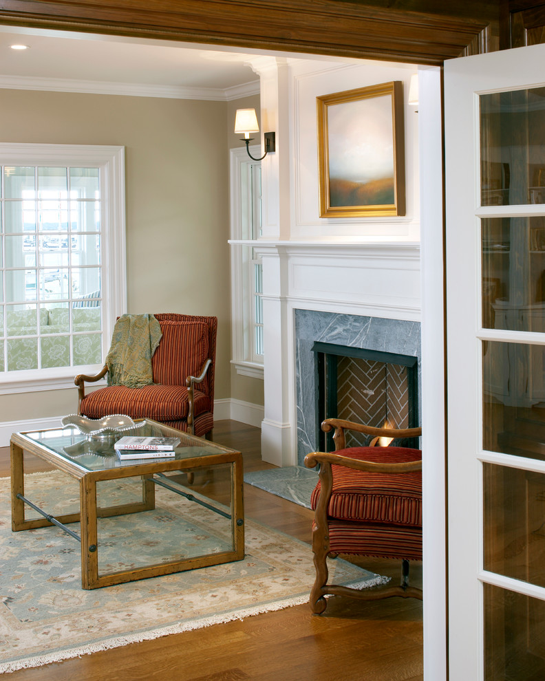 This is an example of a mid-sized beach style enclosed living room in Boston with white walls, medium hardwood floors, a standard fireplace and a stone fireplace surround.