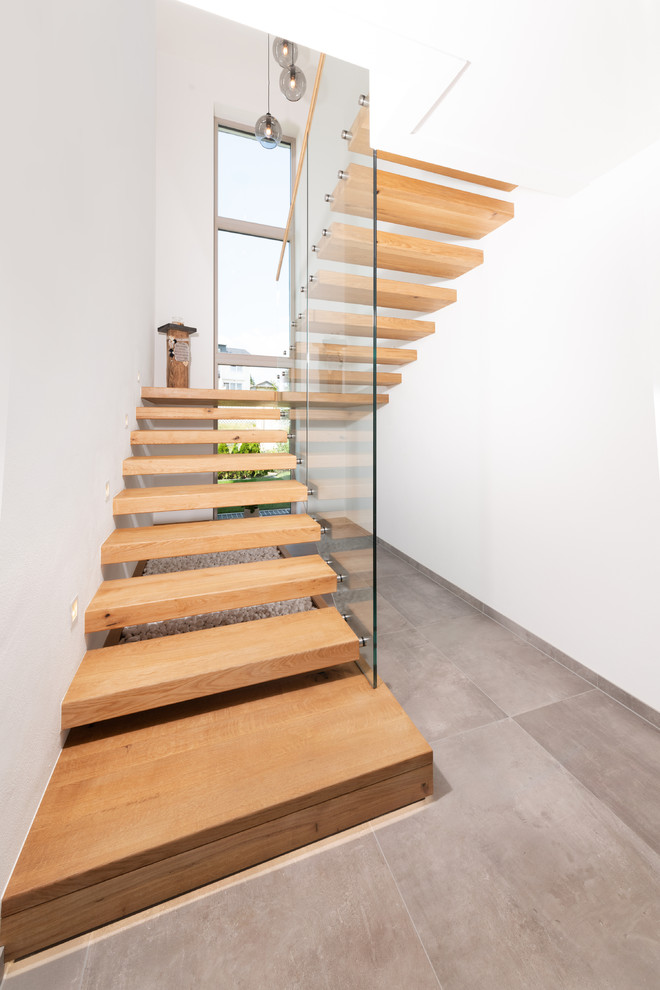 Идея дизайна: большая п-образная лестница в современном стиле с деревянными ступенями и стеклянными перилами без подступенок