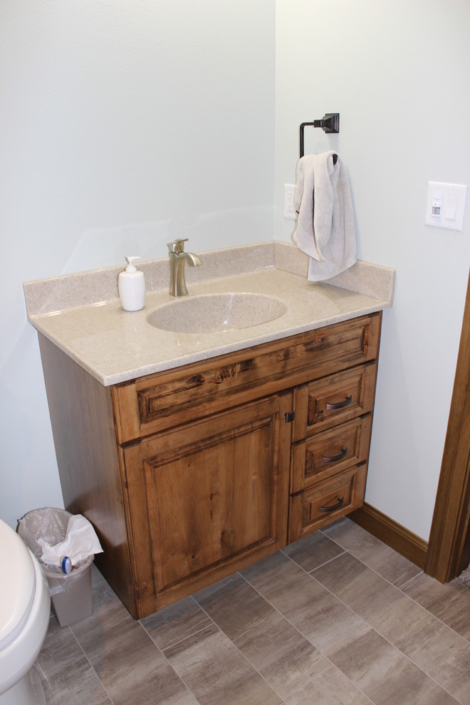 Bathroom - small rustic 3/4 porcelain tile and beige floor bathroom idea with raised-panel cabinets, medium tone wood cabinets, a one-piece toilet, white walls, an integrated sink and laminate countertops