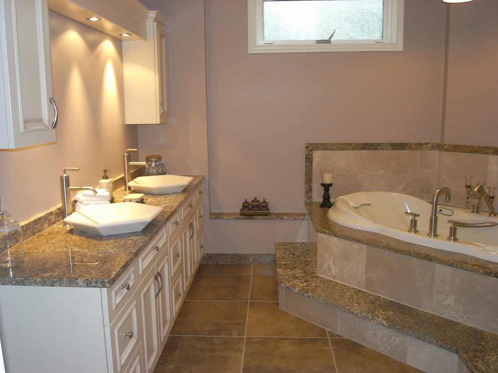 Large transitional master porcelain tile and brown floor corner bathtub photo in Toronto with beige walls, a vessel sink, granite countertops, beaded inset cabinets and white cabinets