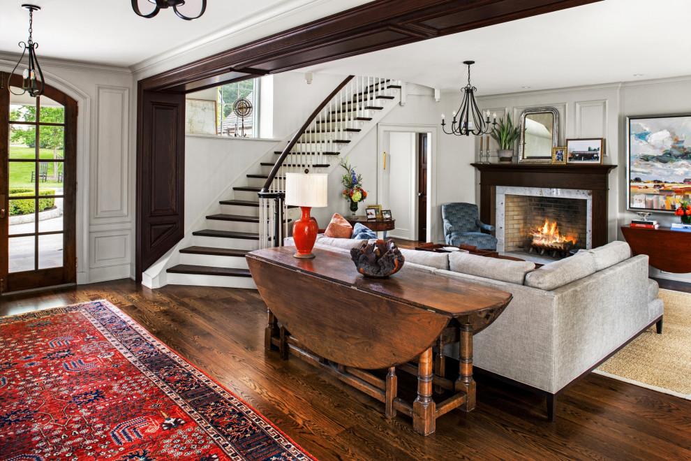 Traditional living room in Philadelphia with white walls, dark hardwood floors, a standard fireplace and brown floor.