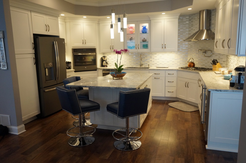 Example of a mid-sized transitional u-shaped medium tone wood floor and brown floor kitchen design with an undermount sink, shaker cabinets, white cabinets, granite countertops, multicolored backsplash, mosaic tile backsplash, stainless steel appliances, an island and gray countertops