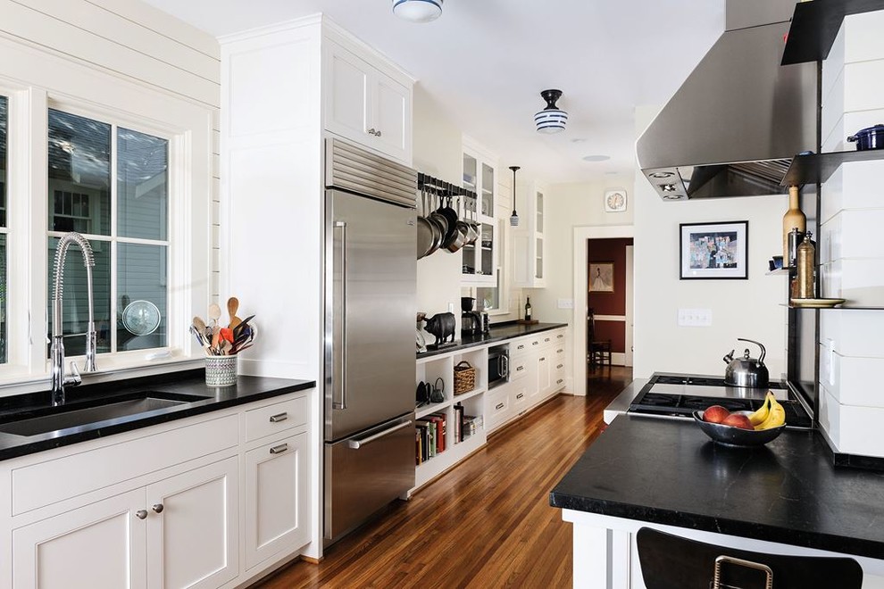 Eat-in kitchen - mid-sized modern galley light wood floor eat-in kitchen idea in Denver with recessed-panel cabinets, white cabinets, black backsplash, cement tile backsplash and stainless steel appliances