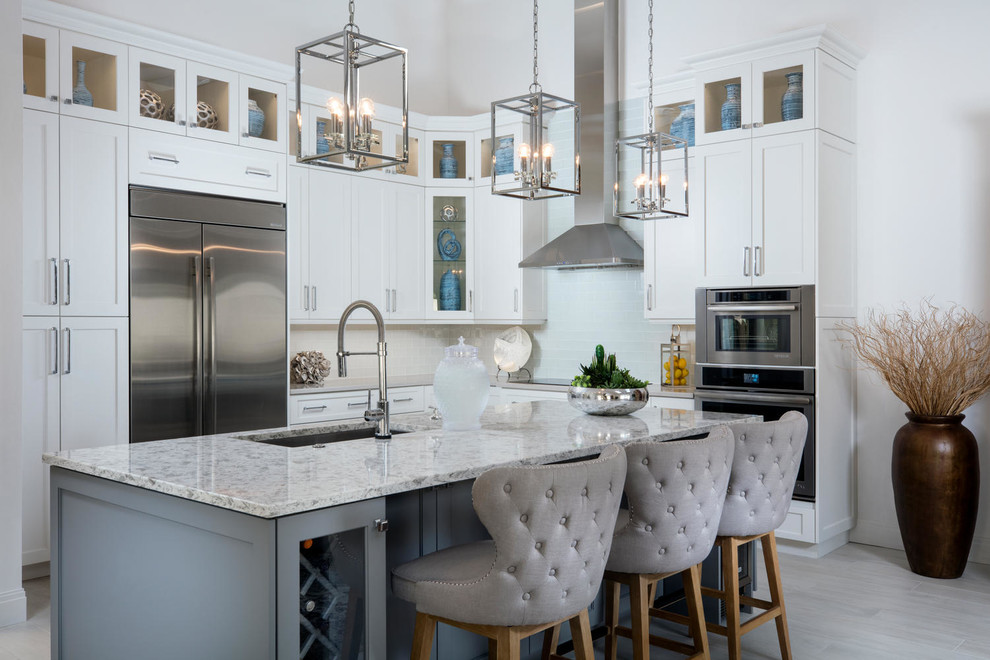 Transitional l-shaped kitchen in Miami with an undermount sink, shaker cabinets, white cabinets, grey splashback, stainless steel appliances, with island, grey floor and grey benchtop.