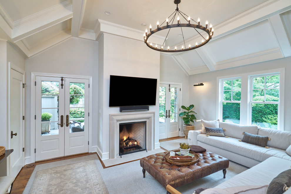 Inspiration for a large traditional enclosed family room in Philadelphia with a home bar, grey walls, medium hardwood floors, a standard fireplace, a plaster fireplace surround, a wall-mounted tv, brown floor and recessed.