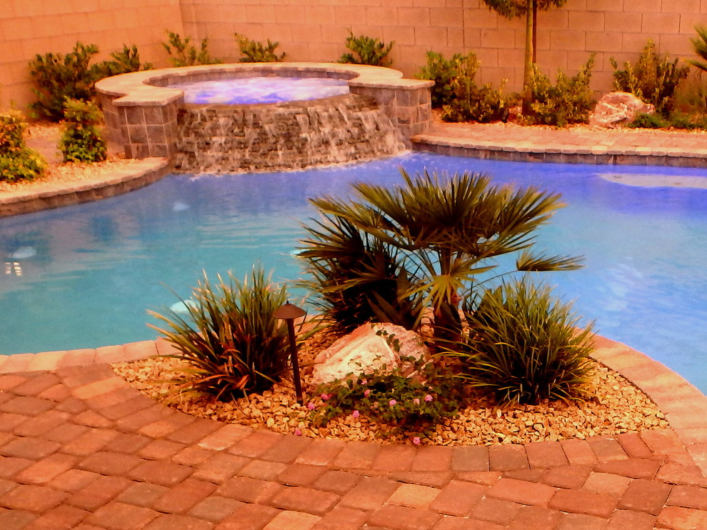 Design ideas for a mid-sized mediterranean backyard custom-shaped pool in Las Vegas with a water feature and brick pavers.