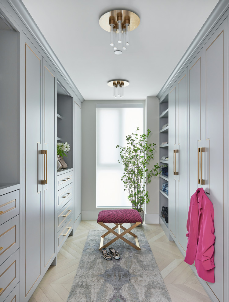 Photo of a large beach style women's walk-in wardrobe in Toronto with flat-panel cabinets, grey cabinets, light hardwood floors and white floor.