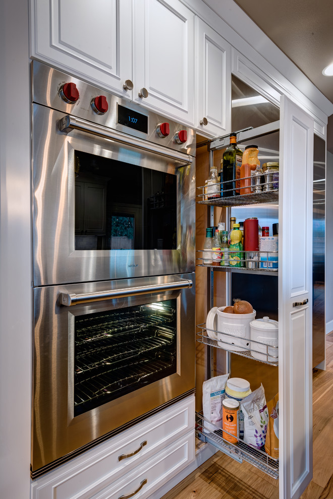 Example of a large transitional u-shaped light wood floor eat-in kitchen design in Seattle with an undermount sink, beaded inset cabinets, blue cabinets, quartz countertops, multicolored backsplash, porcelain backsplash, stainless steel appliances and an island
