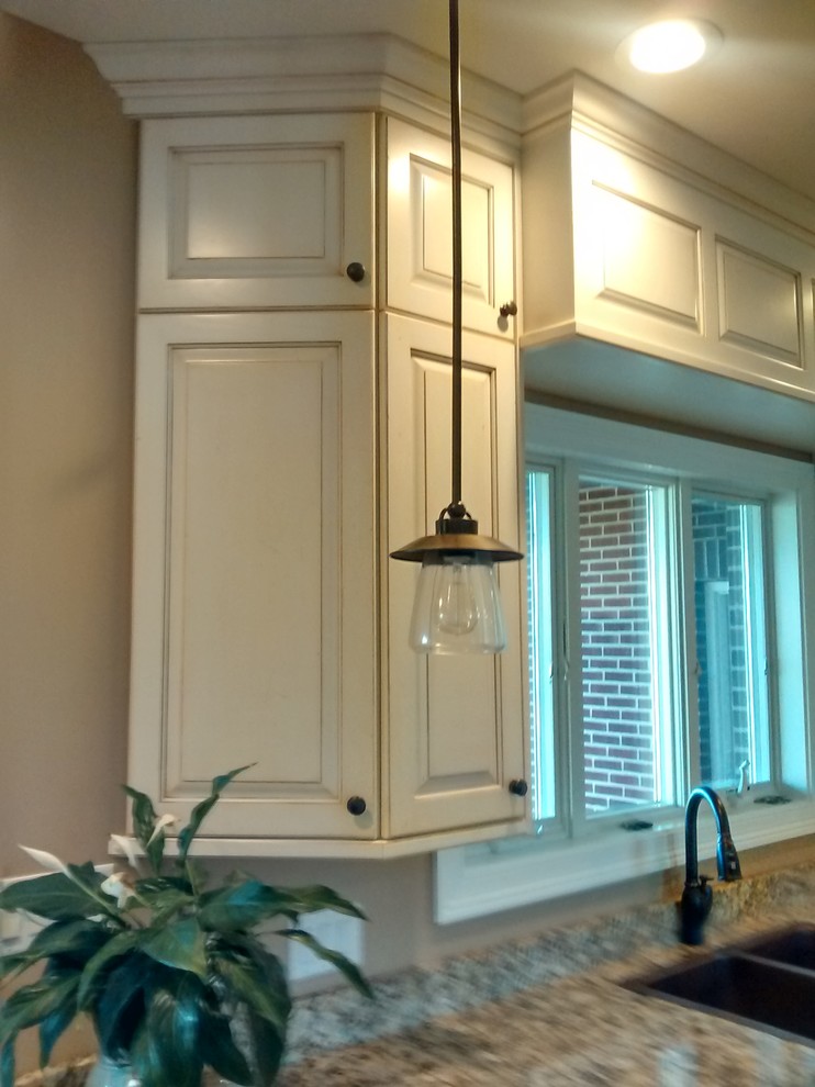 Large transitional l-shaped dark wood floor open concept kitchen photo in Cincinnati with a farmhouse sink, raised-panel cabinets, distressed cabinets, granite countertops, multicolored backsplash, stone slab backsplash, stainless steel appliances and an island
