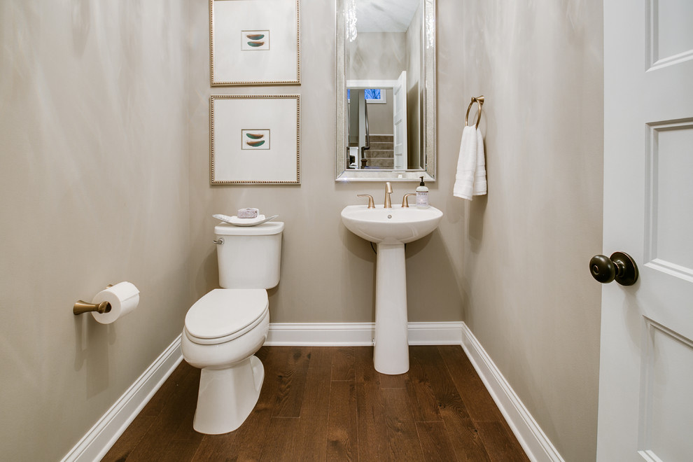 Design ideas for a small transitional powder room in Minneapolis with a two-piece toilet, beige walls, dark hardwood floors, a pedestal sink and brown floor.
