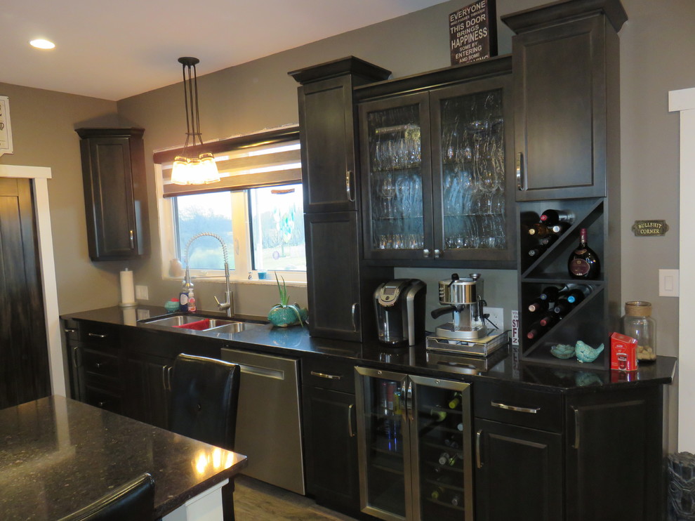 Large transitional l-shaped light wood floor open concept kitchen photo with quartz countertops, stainless steel appliances, an island, a triple-bowl sink, gray cabinets and shaker cabinets