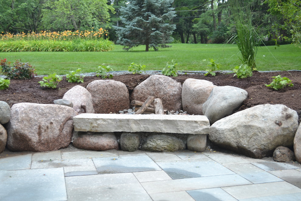 This is an example of a mid-sized rustic backyard stone landscaping in Milwaukee.