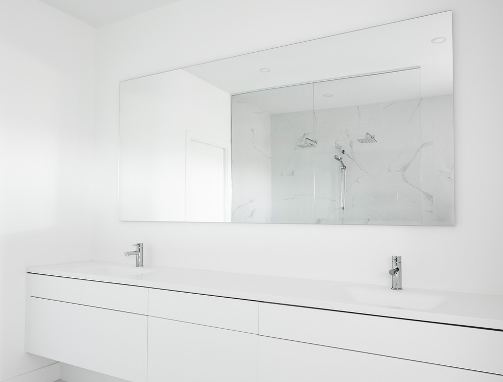 Inspiration for a contemporary master bathroom in Montreal with white cabinets, a freestanding tub, a curbless shower, a one-piece toilet, white tile, marble, white walls, marble floors, white floor, an open shower, white benchtops, flat-panel cabinets, an integrated sink and laminate benchtops.