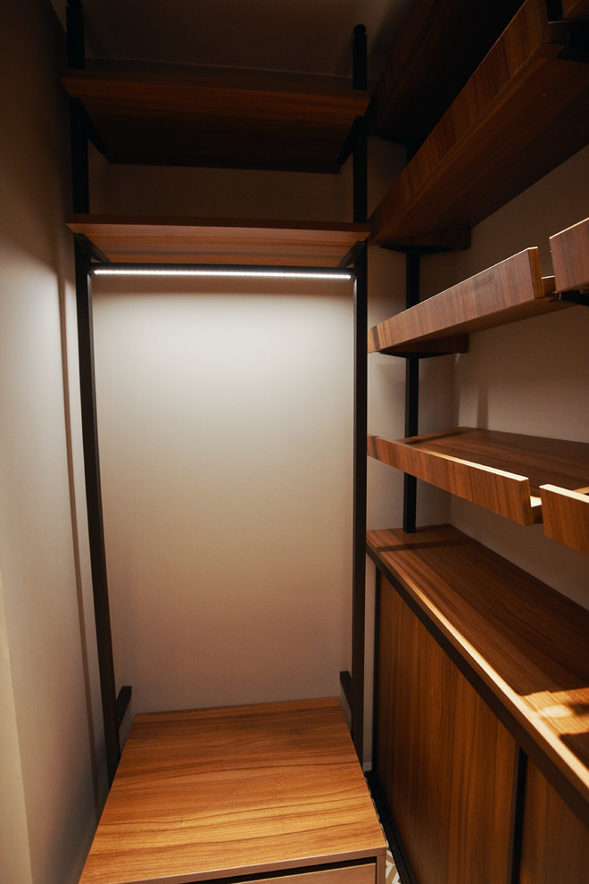 This is an example of a small contemporary walk-in wardrobe in Moscow with medium hardwood floors.