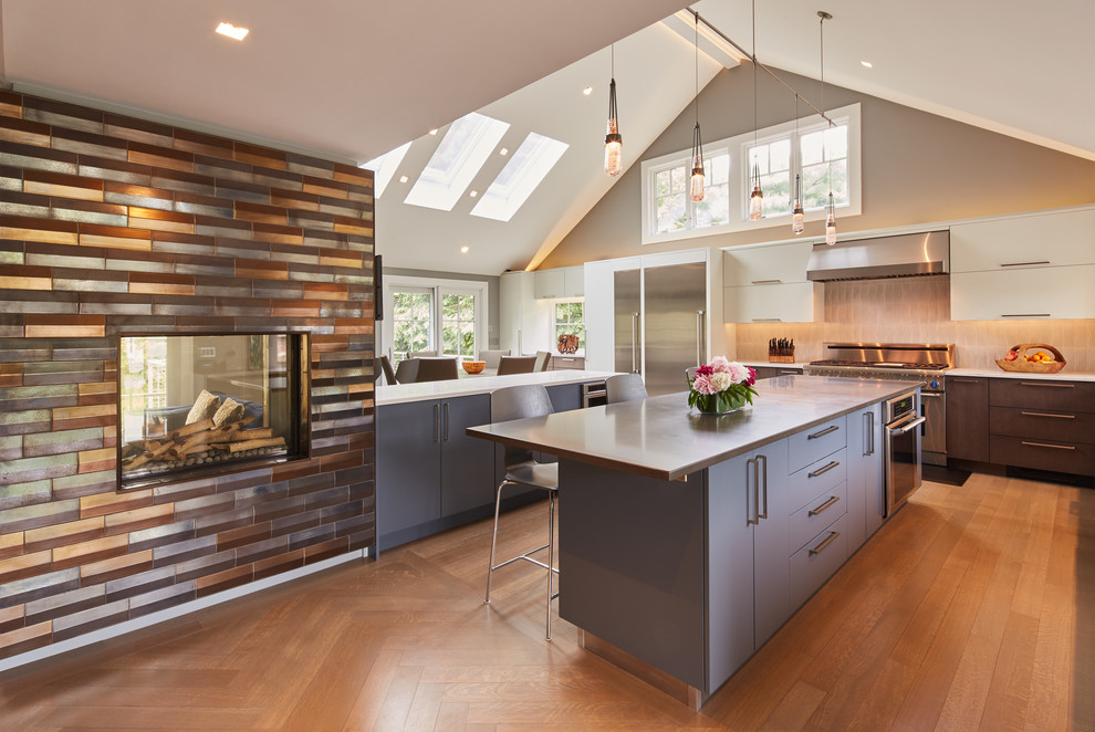 Design ideas for an expansive contemporary open plan kitchen in Boston with light hardwood floors, multiple islands, flat-panel cabinets, white cabinets, beige splashback, stainless steel appliances and white benchtop.