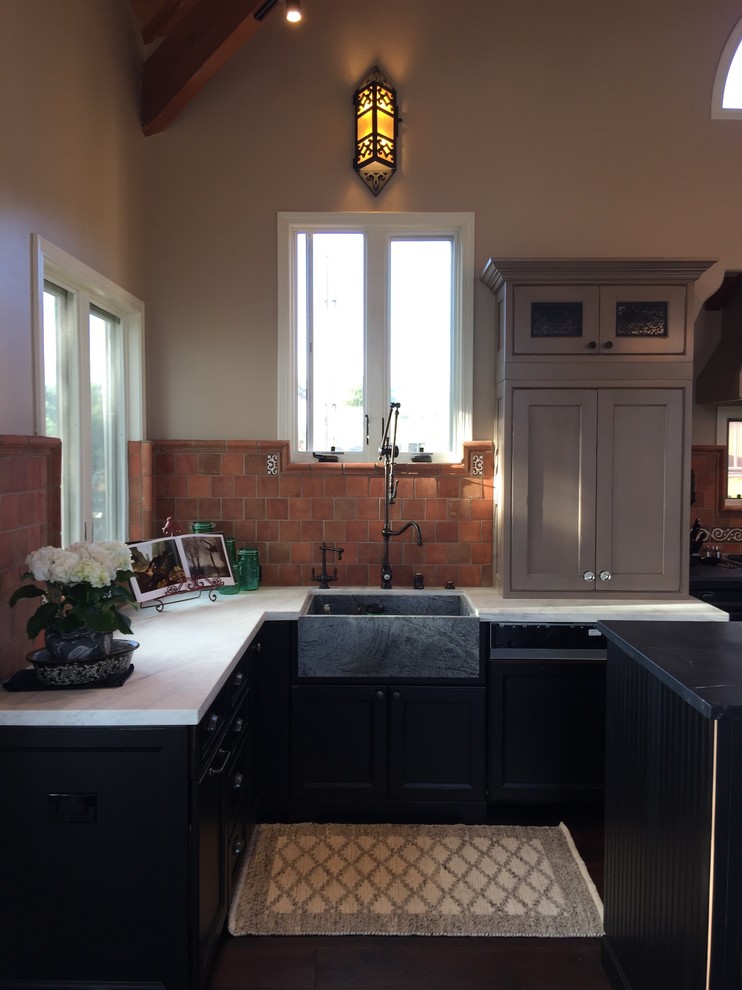 Design ideas for a mid-sized traditional galley open plan kitchen in San Diego with a farmhouse sink, beaded inset cabinets, distressed cabinets, soapstone benchtops, multi-coloured splashback, terra-cotta splashback, stainless steel appliances, dark hardwood floors and with island.