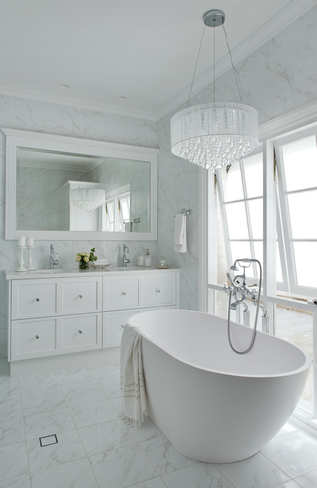 This is an example of a mid-sized contemporary master bathroom in Perth with white cabinets, a freestanding tub, white tile, white walls and marble floors.