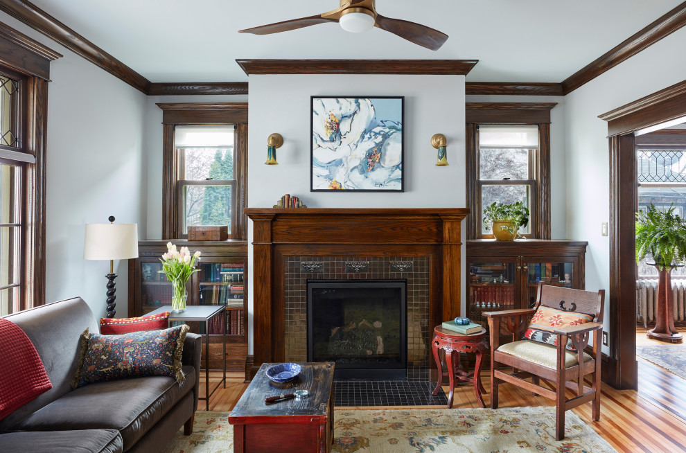 Inspiration for an arts and crafts enclosed living room in Minneapolis with a library, grey walls, light hardwood floors, a standard fireplace, a tile fireplace surround and no tv.