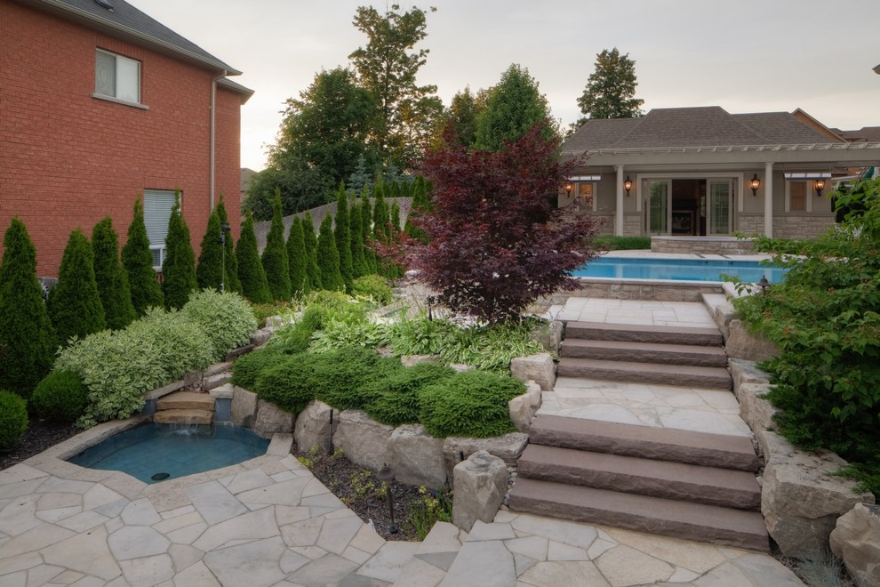 Photo of a large contemporary backyard rectangular infinity pool in Other with a pool house and natural stone pavers.