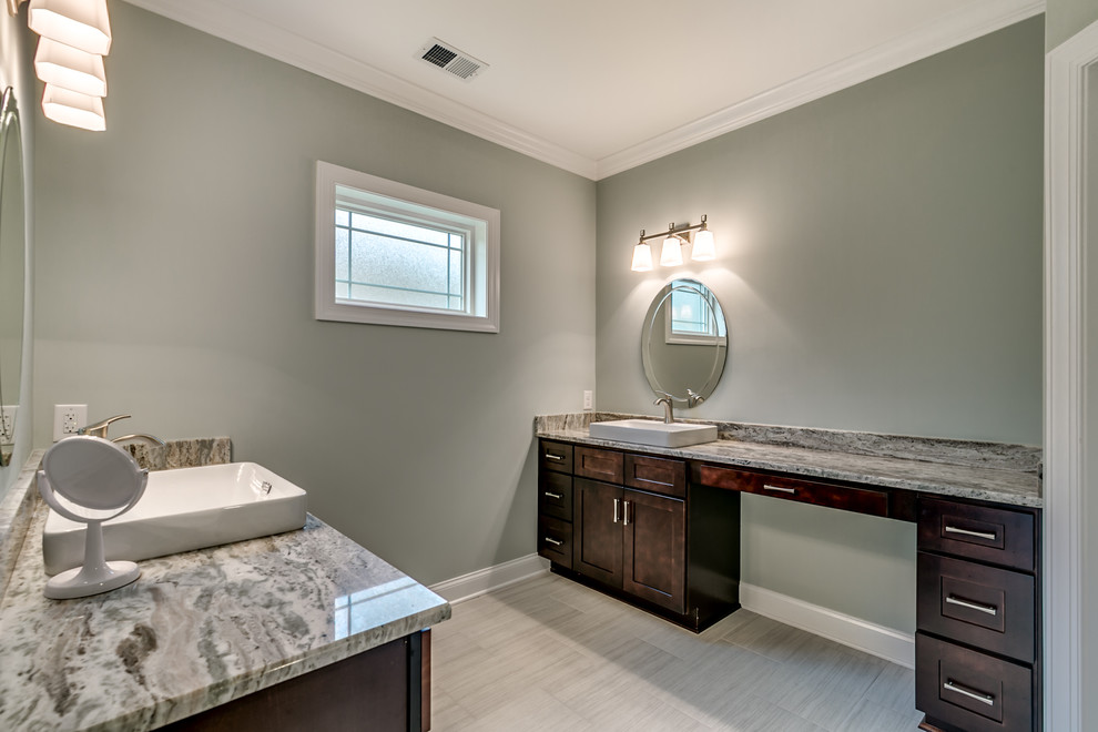 Example of a large transitional master porcelain tile and beige floor bathroom design with shaker cabinets, dark wood cabinets, gray walls, a vessel sink, granite countertops and gray countertops