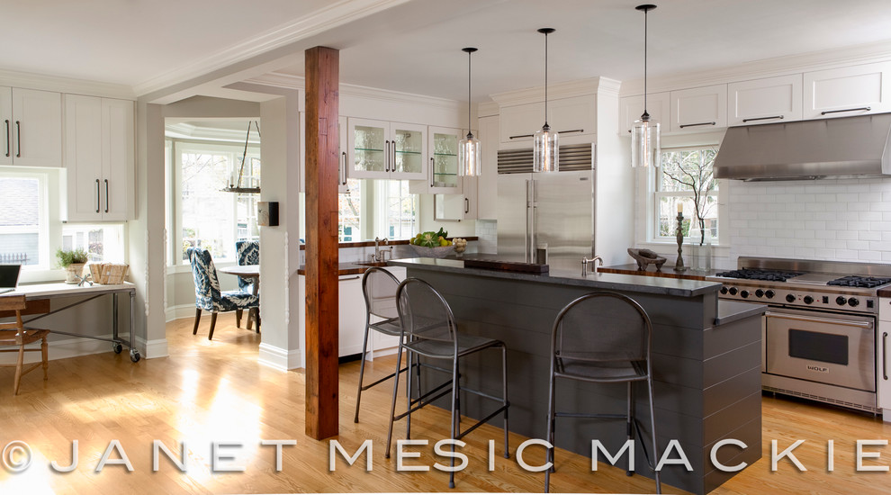 Kitchen - mid-sized transitional light wood floor kitchen idea in Chicago with stainless steel appliances, an island, a farmhouse sink, white cabinets, wood countertops, white backsplash and subway tile backsplash
