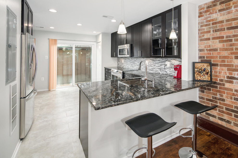 Mid-sized transitional l-shaped porcelain tile enclosed kitchen photo in DC Metro with an undermount sink, shaker cabinets, black cabinets, quartzite countertops, gray backsplash, glass tile backsplash, stainless steel appliances and a peninsula