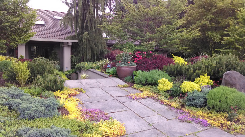 This is an example of a large mediterranean front yard full sun garden in Seattle with natural stone pavers and a retaining wall.