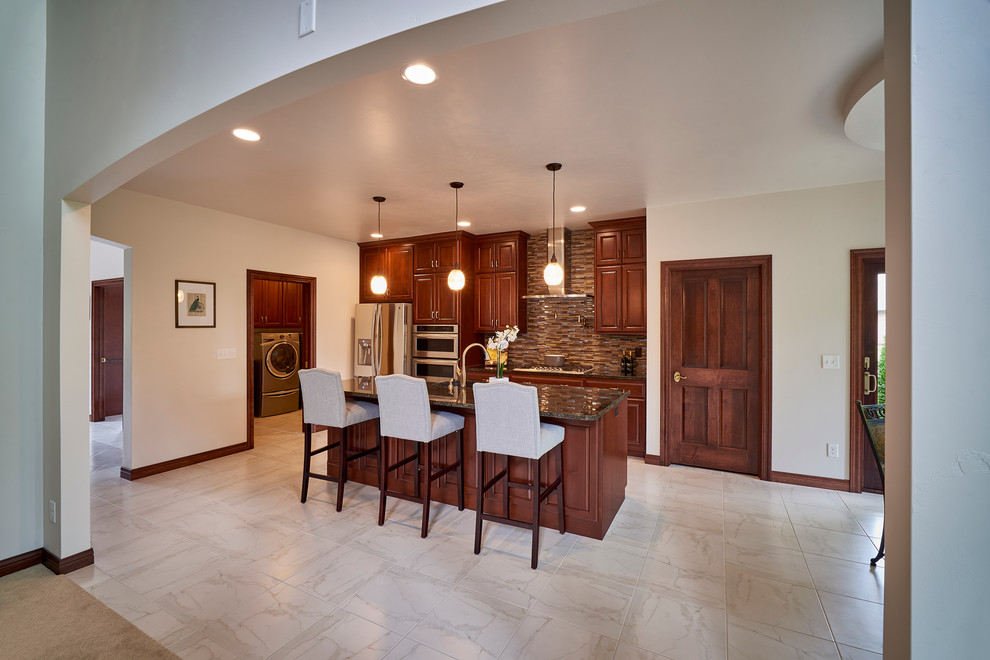 Mid-sized transitional galley porcelain tile open concept kitchen photo with an undermount sink, raised-panel cabinets, dark wood cabinets, granite countertops, brown backsplash, mosaic tile backsplash, stainless steel appliances and an island