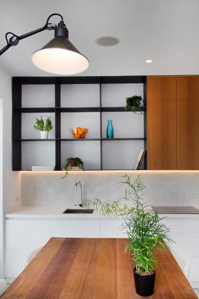 Inspiration for a small contemporary l-shaped open plan kitchen in Madrid with an undermount sink, flat-panel cabinets, dark wood cabinets, quartz benchtops, beige splashback, terra-cotta splashback, black appliances and white benchtop.