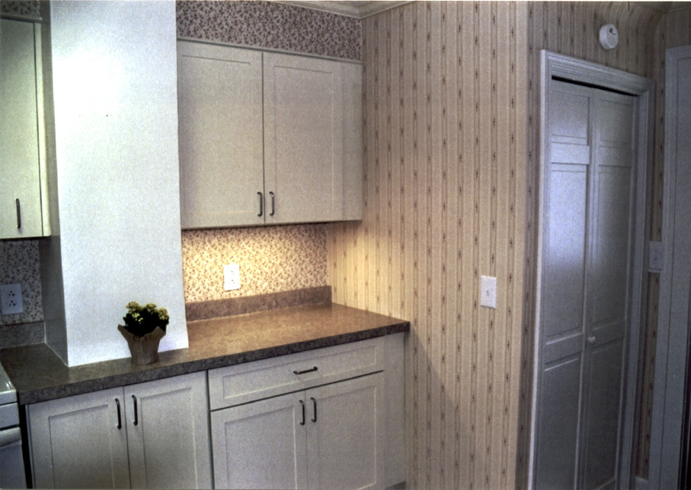 Example of a mid-sized transitional l-shaped medium tone wood floor and brown floor kitchen pantry design with a double-bowl sink, recessed-panel cabinets, white cabinets, laminate countertops, brown backsplash, white appliances, no island and brown countertops