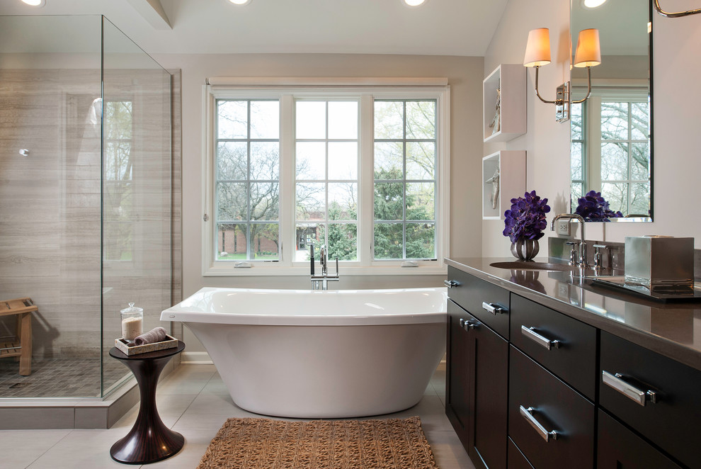 Design ideas for a transitional master bathroom in Chicago with an undermount sink, flat-panel cabinets, dark wood cabinets, engineered quartz benchtops, a freestanding tub, a corner shower, gray tile, stone slab, porcelain floors and beige walls.