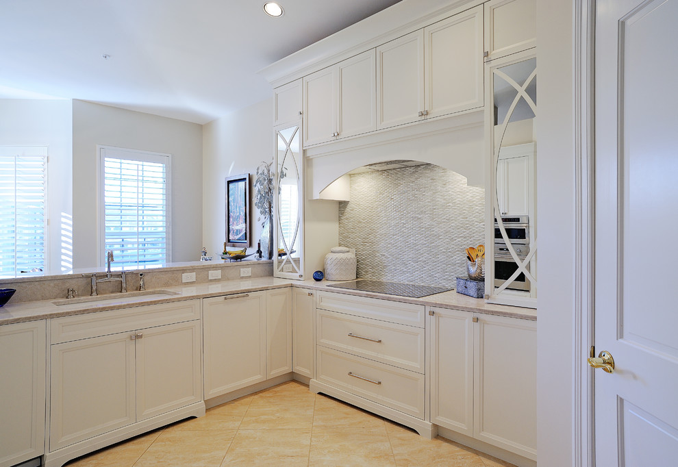 Example of a mid-sized transitional l-shaped eat-in kitchen design in Miami with a double-bowl sink, recessed-panel cabinets, white cabinets, quartzite countertops, white backsplash, glass tile backsplash, paneled appliances and a peninsula
